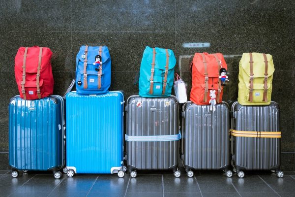 5 wheelie bags with backpacks sitting on top