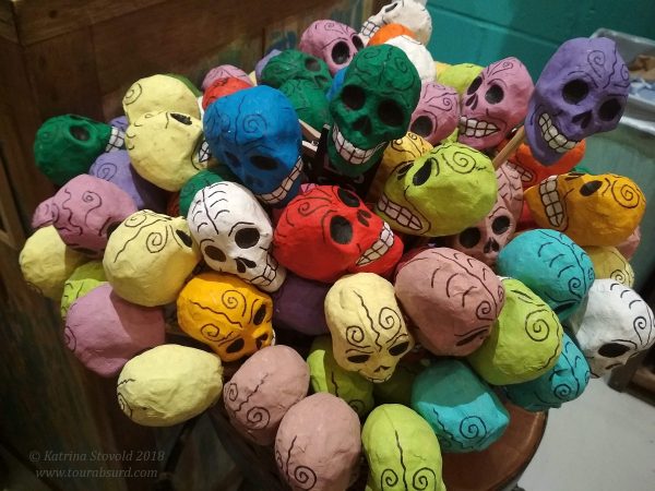 A large container full of colourful papier-mâché maracas, decorated like Día de Muertos skulls.